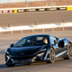 A black McLaren Artura being driven on a racetrack.